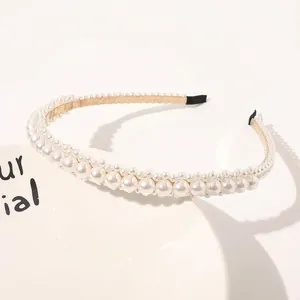 Detailed view of triple-row white pearl headband with gold ribbon and black rubber tips