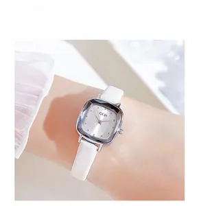 Close-up of minimalist square silver watch dial with white leather strap on wrist