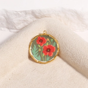 Detail of a vintage-style gold textured floral pendant with red enamel flower on fabric