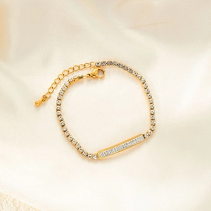 Macro view of gold chain bracelet with sparkling crystal inlay on silk fabric background