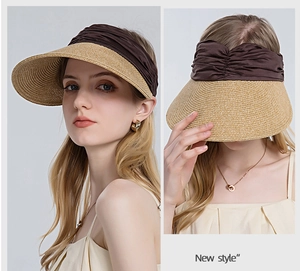 Detail of wide brim straw sun visor with dark brown pleated band and spiral weave pattern