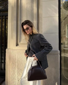 Gros plan détaillé sur un blazer à carreaux gris foncé avec pantalon large et sac en cuir