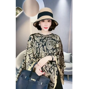 Detail eines Paisley-Musterschals in Schwarz und Gold aus seidigem Stoff mit Glanzeffekt