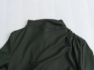Detail of dark pleated midi dress featuring a sophisticated high-neck collar and fabric texture