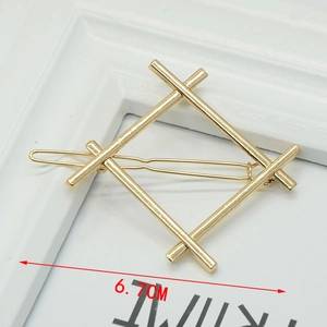 Detail of a 6.7cm golden geometric diamond-shaped metal hair clip on a white frame