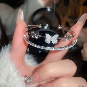Macro detail of double-layer silver bracelet with shell butterfly and pavé crystals