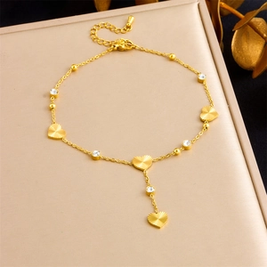 Détail d'une chevillère en acier doré avec pendentifs en cœur et breloques en cristal