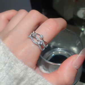 Detail of wave layered ring with cubic zirconia and pearls on hand with glass