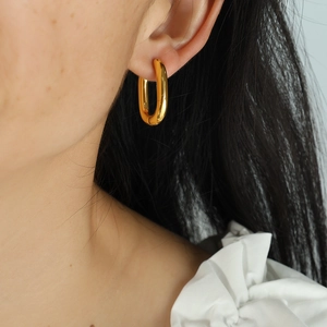 Elegant U-shaped gold plated titanium steel hoop earrings on model with polished finish