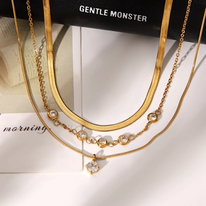 Detail of layered gold necklaces with zircon stones and polished snake chain texture