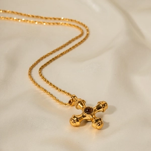 Macro detail of 18k gold plated stainless steel cross pendant with dark tiger eye stone