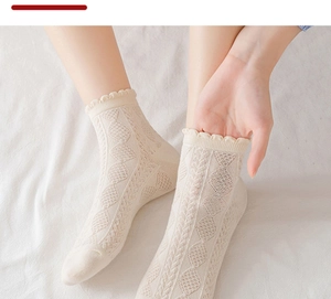 Detail of beige lace socks with hollow heart patterns and elastic ruffled cuffs