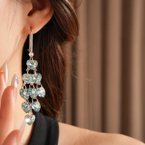 Detail of sea blue heart crystal tassel earrings with zircon studs on model