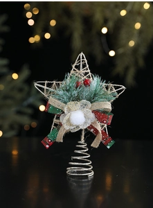 Detail of glittery iron star tree topper with pine needles and festive red bow