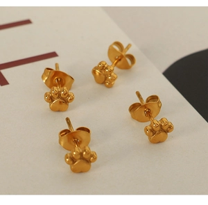 Vue macro de boucles d'oreilles en forme de patte de chat dorées 18 carats sur support