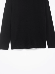 Detailed view of the smooth knitted hem and sleeve cuff on a black long sleeve top
