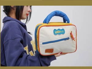 Detail view of colorful makeup bag with blue cloud patch, zipper pocket, and sturdy handle