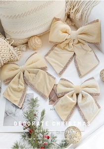 Three beige velvet Christmas bows with gold glitter edges in various sizes on soft fabric