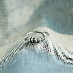 Detailed macro shot of silver spinner ring with five sparkling zircon beads for anxiety relief