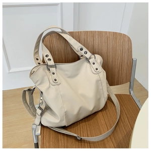 Detail of the cream faux leather tote bag on a wooden chair in a minimalist room