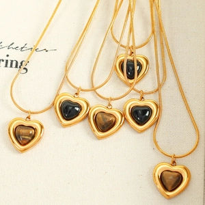 French vintage tiger eye heart necklace with golden snake chain on canvas background