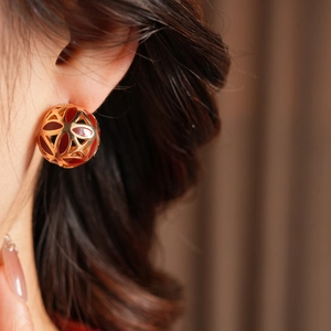 Détail de la boucle d'oreille vintage fleur dorée avec émail rouge sur le mannequin