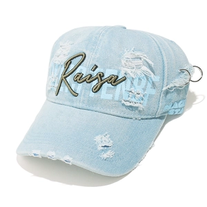 Detailed view of light blue washed denim cap with vintage embroidery and metal rings