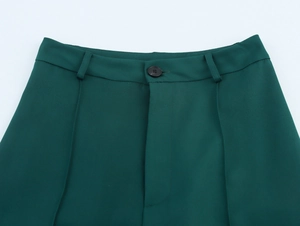 Detail shot of green trousers waist with black button and precise stitching work
