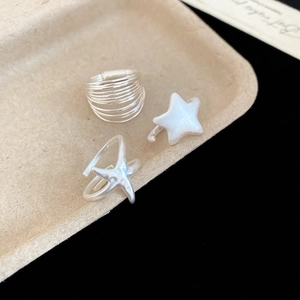 Detailed view of silver multi-layer spiral and starfish open rings on textured tray