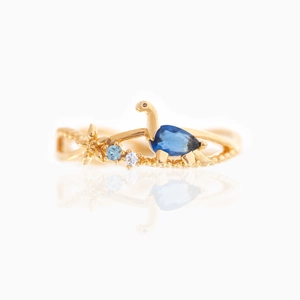 Detailed view of an 18K gold-plated dinosaur ring with a blue teardrop zircon stone