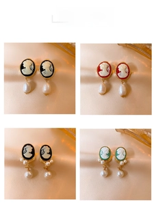 Detailed view of vintage cameo earrings with portrait relief and pearl drops on satin