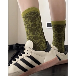 Detail of green crew socks with dark green scroll patterns worn with retro sneakers
