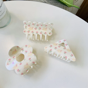 Detailed close-up of three floral acrylic hair claws with pink rose and duck patterns