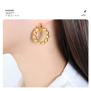 Close-up of model wearing gold twisted rope hoop earrings with polished finish