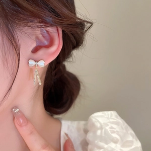 Détail de boucle d'oreille nœud avec finition nacre blanche et franges scintillantes