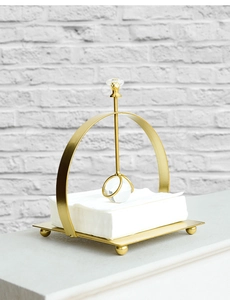 Detail of gold metal napkin holder with crystal ball gravity weight on white napkins