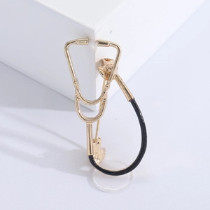 Detailed view of stethoscope brooch with golden ear hooks and black connecting tube