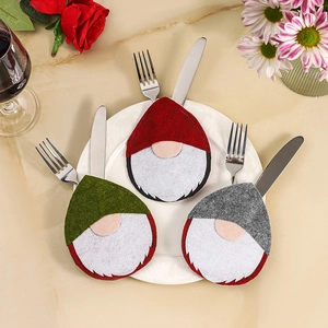 Three Christmas gnome cutlery holders in red, green, and grey on a festive table set