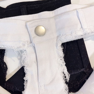 Gros plan sur les ourlets effilochés et boutons métalliques de shorts en jean noir et blanc