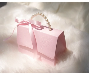 Detail of pink gift box with pearl handle and ribbon on white faux fur background