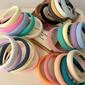 Padded sponge headbands in multiple pastel colors arranged on a rustic wooden tray