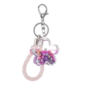 Acrylic flower quicksand keychain with purple liquid and macaron beads on white backdrop