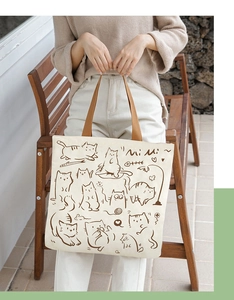 Detail of off-white canvas tote with brown woven handles and cat illustrations