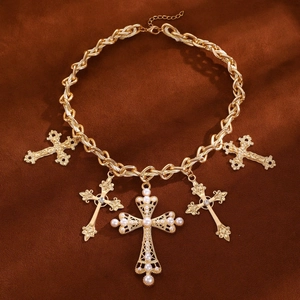 Detailed close-up of a golden layered cross necklace with white pearls on brown velvet