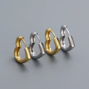 Polished S925 silver heart earrings in gold and silver finishes on a grey background