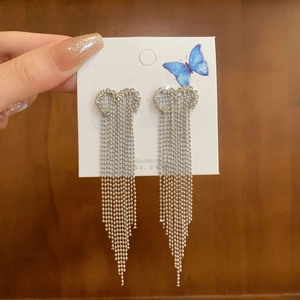 Detailed close-up of sparkling silver heart-shaped tassel earrings with pavé crystals