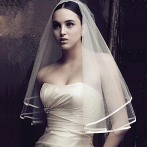 Detail of elegant two-layer ivory bridal veil with satin edge and soft tulle fabric