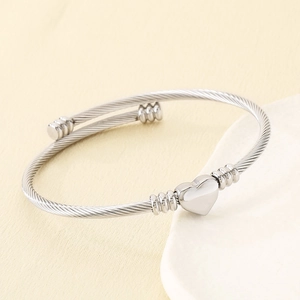 Vue macro d'un bracelet câble torsadé argenté avec pendentif cœur en acier inoxydable