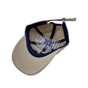 Detail view of the beige baseball cap interior with black sweatband and metal buckle