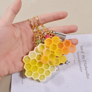 Porte-clés abeille alvéolé en acrylique avec anneau doré et gland en cuir sur livre